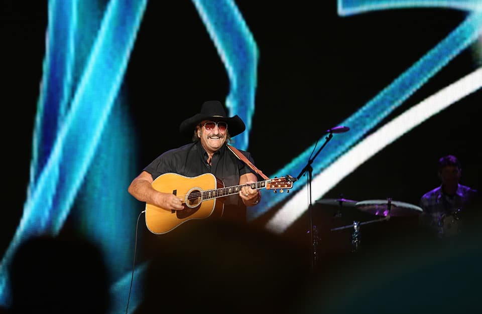 Dennis Agajanian gives the crowd a smile as they clap to his fast guitar picking.