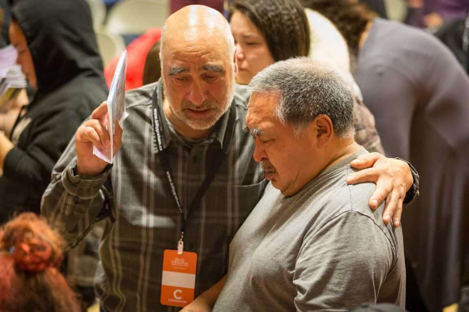 A prayer volunteer prays with a man who came forward at Saturday night's invitation to receive Christ as Lord and Savior.