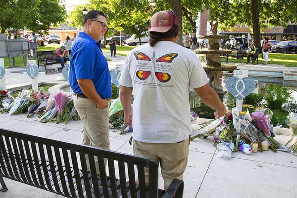 A Billy Graham chaplain talks with a man who stopped by the Uvalde town square where a memorial is set up for the 21 people who lost their lives in a south Texas school shooting.