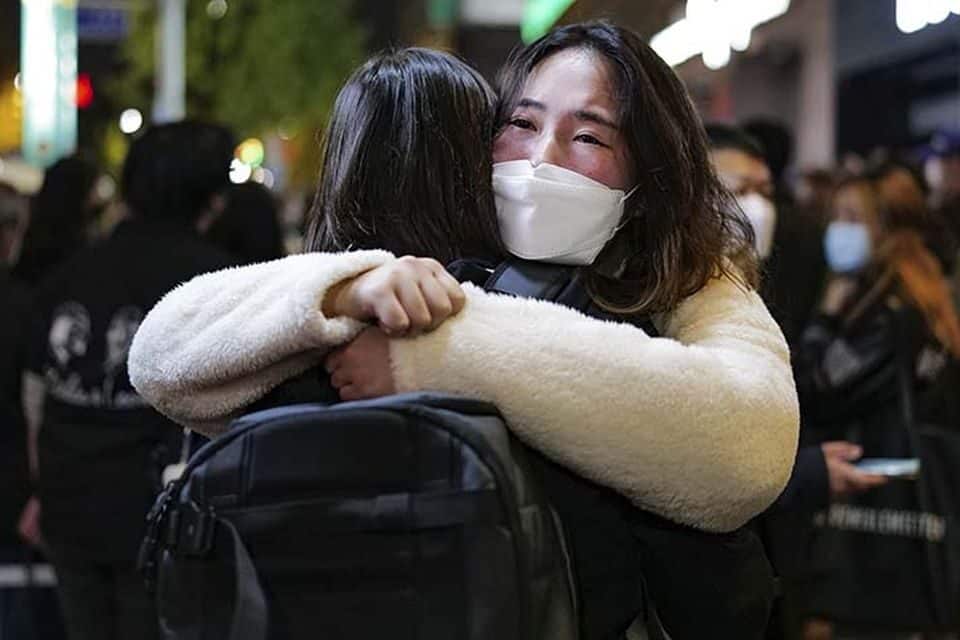 A woman who survived the Seoul crowd crush (right) hugs a friend after a tragic night. (Photo: Chris Jung)