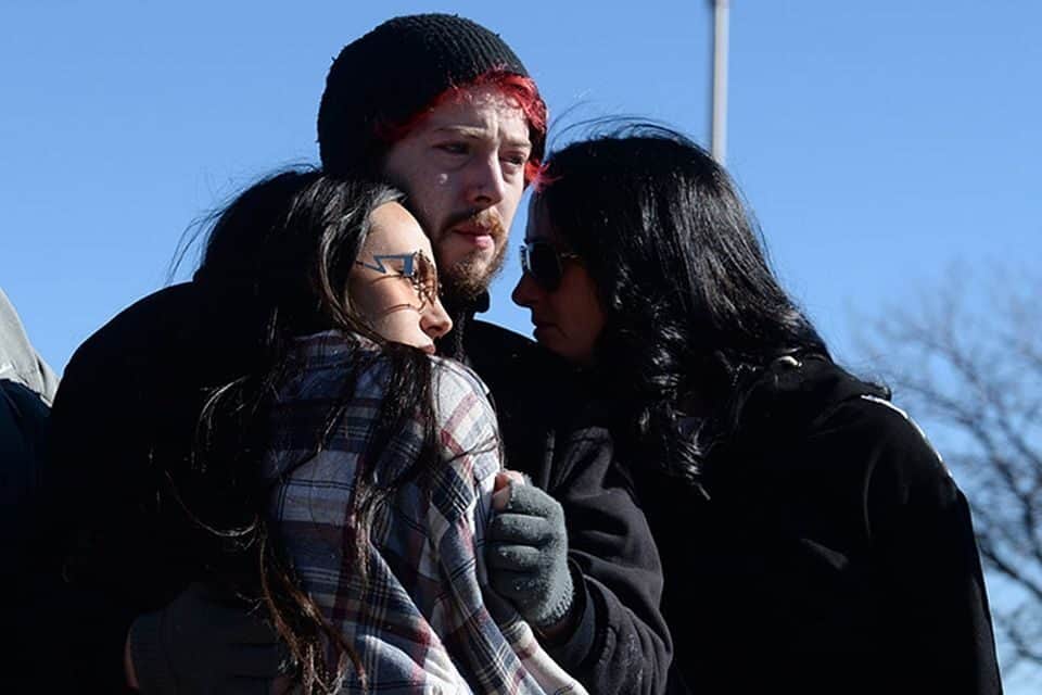 A group huddles in grief at a makeshift memorial after a shooter killed five people at a nightclub on Saturday. (AP Photo/Geneva Heffernan)