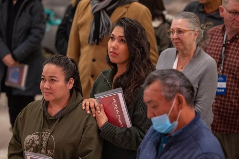 A young woman holds a booklet called Living in Christ, which is given to everyone who decides to put their faith and trust in Jesus. The booklet—which includes a study of the gospel of John—offers Biblical guidance on how new believers can grow in their faith in the days ahead.