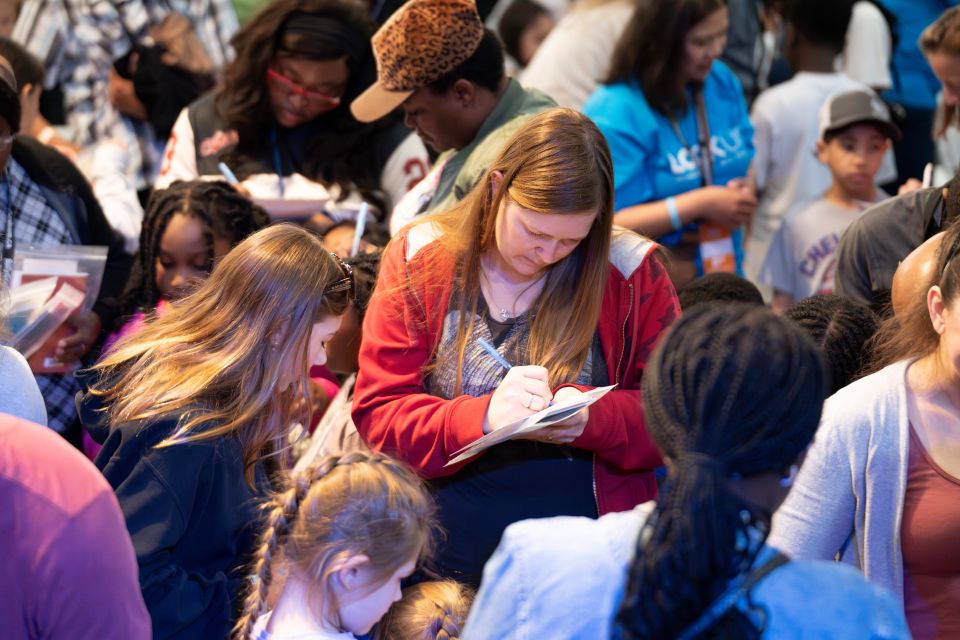 Parents and volunteers help their children fill out response cards after praying to receive Christ.